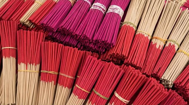 Vibrant Bundles of Traditional Aromatic Incense Sticks in Red, Magenta, and Natural Tones, Ready for Cultural or Spiritual Ceremonies and Offerings