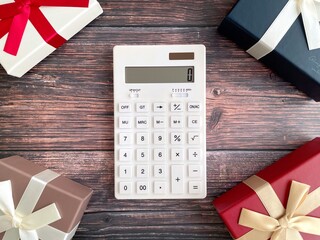 Calculator and gift boxes on wooden background, budgeting for presents