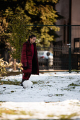 Young girl rolling snow ball for snowman