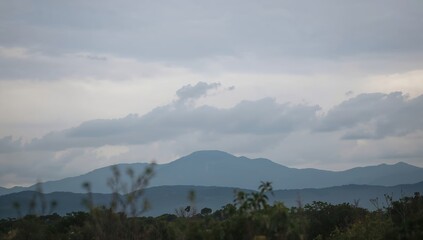 Mountains under a cloudy sky create a serene landscape. The scene evokes a feeling of calm and peace