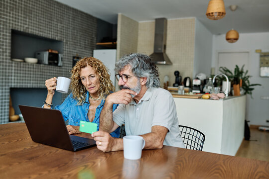 portrait of happy smiling senior elderly couple using a laptop computer and a credit card  for online shopping at home, technology and internet use in everyday life concept - Powered by Adobe