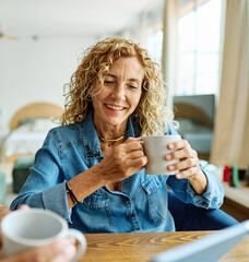 Portrait of a lovely tablet senior mature couple using a laptop together and having fun drinking...