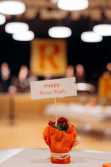 Festive New Year decoration with a greeting card in a blurred ballroom interior with warm bokeh light