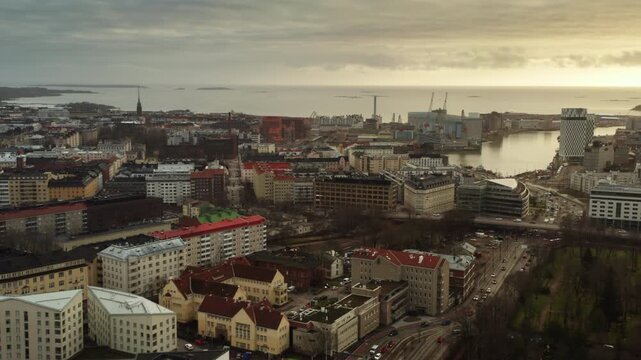 Ruoholahti district buildings and West Harbour with Clarion Hotel tower in Helsinki at sunset, Finland capital city urban landscape overlooking Baltic sea under cloudy sky in winter.