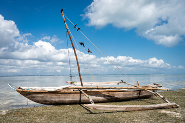A classic Zanzibar outrigger boat dhow standing on the shore during low tide, reflecting the rich maritime culture and traditional fishing of East Africa.