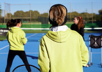 TENNIS CONCEPT. Faceless image of adult women with their backs turned, taking a tennis lesson.