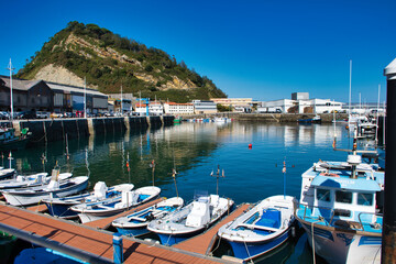 Obraz premium The picturesque fishing port of Getaria, with colorful boats bobbing in the water against the iconic silhouette of 