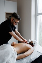 Therapist performing deep tissue back massage on woman