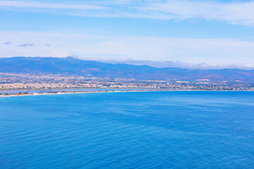 Fototapeta premium Coastline along Golfo degli Angeli, showcasing Poetto beach in Cagliari, Sardinia, Italy, blue waters and mountain backdrop. Natural beauty and urban convenience of one of Europe largest city beaches