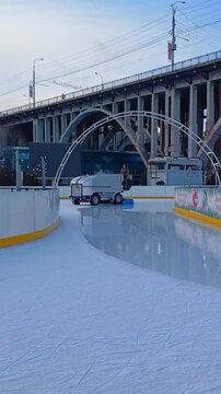 An ice harvester fills the ice at the city skating rink. The ice filling machine drives around the ice rink and renews the ice coating
