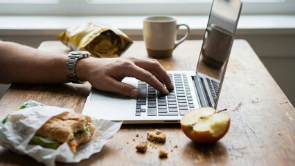 Office desk remote work laptop computer messy table chaotic workspace lived spaces casual lunch home office male hand typing office desk chaotic