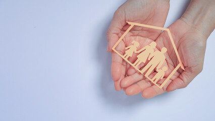 Hands holding  paper family cutout  symbolizing mental health safe home. Caring protection with love ensures security plus happy life planning © Piya W.