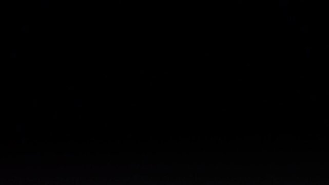 Out of focus police light bar flashing red and blue at the bottom of the frame, with a large black area above for text or titles, creating a cinematic night background.