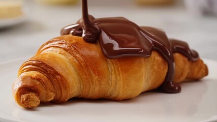 Dripping chocolate over fresh croissant capturing delicious dessert moment