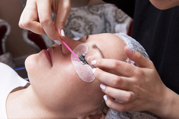Fashionable lady receiving eyelash extensions at beauty salon.