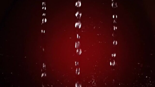 Juicy pomegranate arils rising with a dramatic water splash in slow motion