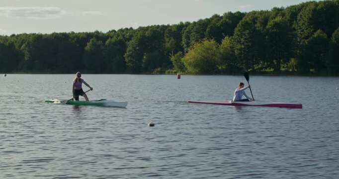 The girls are paddling hard during training.. Two women in a canoe and a kayak paddle along the river, actively working on rowing technique.