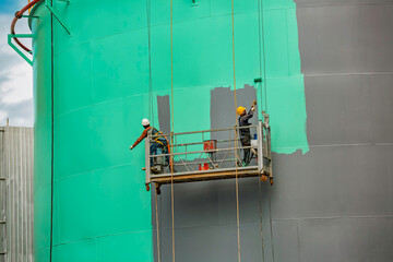 The male worker takes the cable car holding an industrial painting brush used for shell plate tank oil surface surface green