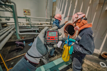 Worker hand holding gas detector inspection safety gas testing at front manhole