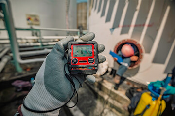Worker hand holding gas detector inspection safety gas testing at front manhole © chitsanupong