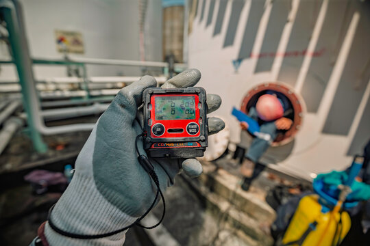Worker hand holding gas detector inspection safety gas testing at front manhole
