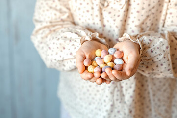 Child holding handful of Multi-Colored chocolate eggs. Easter and spring concept.