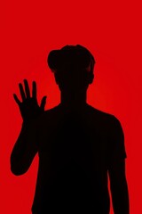 A striking silhouette of a person fully immersed in a virtual reality experience, depicted against a bold, vibrant red background. The individual wears a modern VR headset, and one hand is raised with