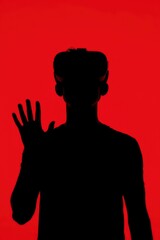 A striking silhouette of an individual wearing a modern virtual reality headset against a vibrant, bold red background, extending a hand as if interacting with an unseen digital interface. This powerf