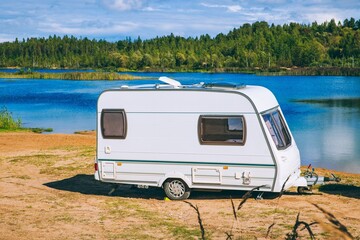 A Peaceful Lakeside Camping Scene Featuring a Charming White Caravan by the Water's Edge