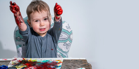 Child raising messy painted hands, expressing happiness, artistic freedom, imagination, and emotional creativity through play. Copy space.
