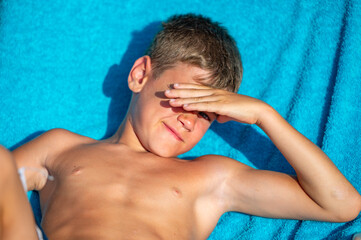 a little tanned boy lies on a sun lounger