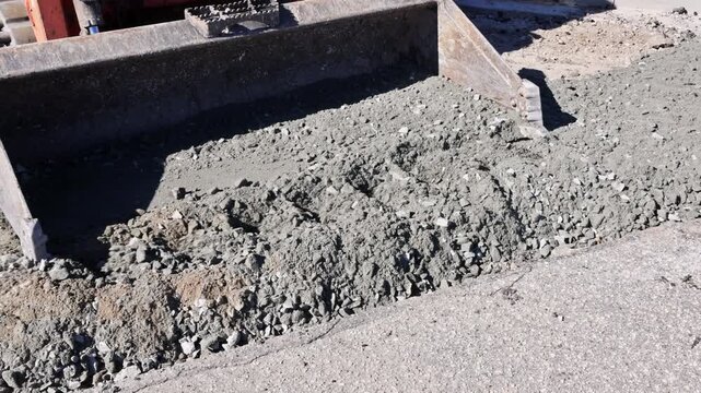Heavy tractor machinery digs prepares road surface with gravel concrete in construction area under road works