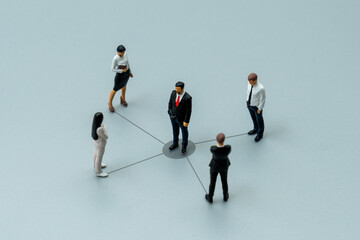 Miniature business people connected by lines to a central leader. The delegation of tasks, distribution of responsibilities, and effective team management concept.