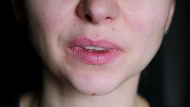 A yawning woman covers her mouth with her palm close-up. Concept of fatigue and poor sleep. Movement of female face muscles, mouth and tongue. Overwork at work. Poor room ventilation. Boring film. 4K