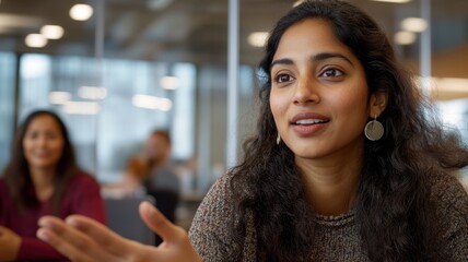 Young South Asian woman contributing ideas in a board meeting with a focus on fresh perspectives and inclusion