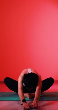 A girl performs a butterfly stretching yoga exercise in a vertical 4K video. The footage highlights flexibility, relaxation, and mindfulness through a calm stretching movement. Ideal for concepts rela