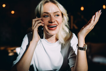 Laughing woman holding smartphone while communicating during remote work at café, representing joy, connection, and creative engagement in flexible digital professional lifestyle