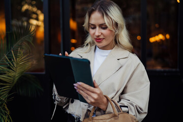 Portrait of woman studying tablet screen, soft light on her face. Scene conveys calm focus, technology empowerment, and the grounded pace of freelance work © BullRun