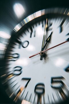 Close up of clock hands moving fast with motion blur effect representing time passing quickly or deadline pressure and fast pace of life