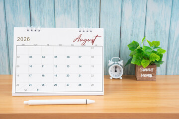 August Monthly desk calendar for 2026 year and alarm clock.