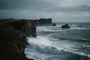 Obraz premium Dramatic coastal cliffs battered by a tumultuous ocean under a moody, overcast sky