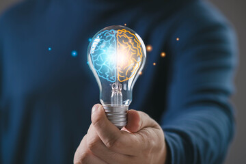 Hand holding light bulb with glowing human brain inside, symbol of intelligence, creativity and analytical thinking, representing smart ideas, innovation, balanced mind for future technology business. © Bordinthorn
