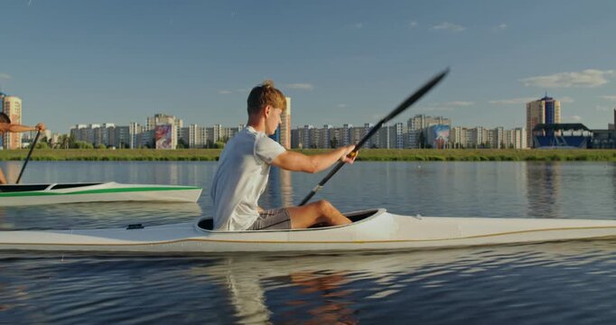 Close-up of a rower in a kayak during training on the water.. Men in a kayak and canoe train technique and pace, confidently paddling along the river.