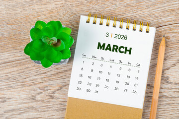 March 2026 monthly desk calendar and pencil with plant pot decoration.