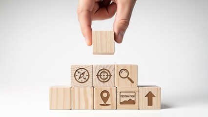 Hand placing wooden block on stack with navigation symbols for planning journey or achieving business goals effectively and efficiently.