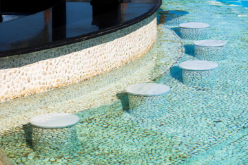 A pool bar with seats in the water.