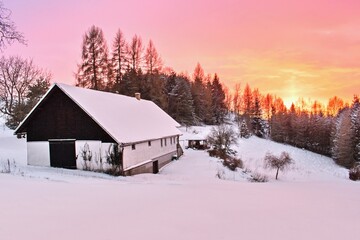 Czech countryside landscape with traditional rural house. Colorful winter sunset in Orlicke mountains. Carpathian region
