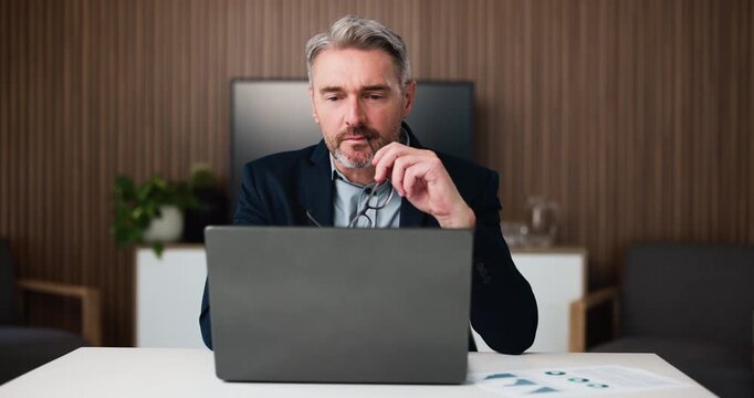 Businessman, glasses or paperwork in office with laptop for data analysis, financial report or audit. Mature person, eyewear or problem solving with computer for finance document, stats or accounting