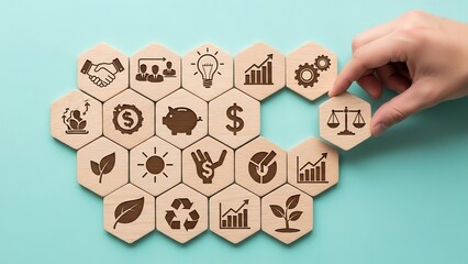 Hand arranging wooden hexagonal tiles with various business and finance icons in a puzzle pattern symbolizing strategic planning and financial growth.