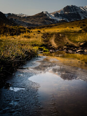 Clouds and mist surround the mountain peaks, while a babbling stream flows through the golden wilderness a dreamlike autumn.